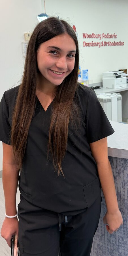 Alexa, the author, smiling in scrubs at a pediatric dentistry office
